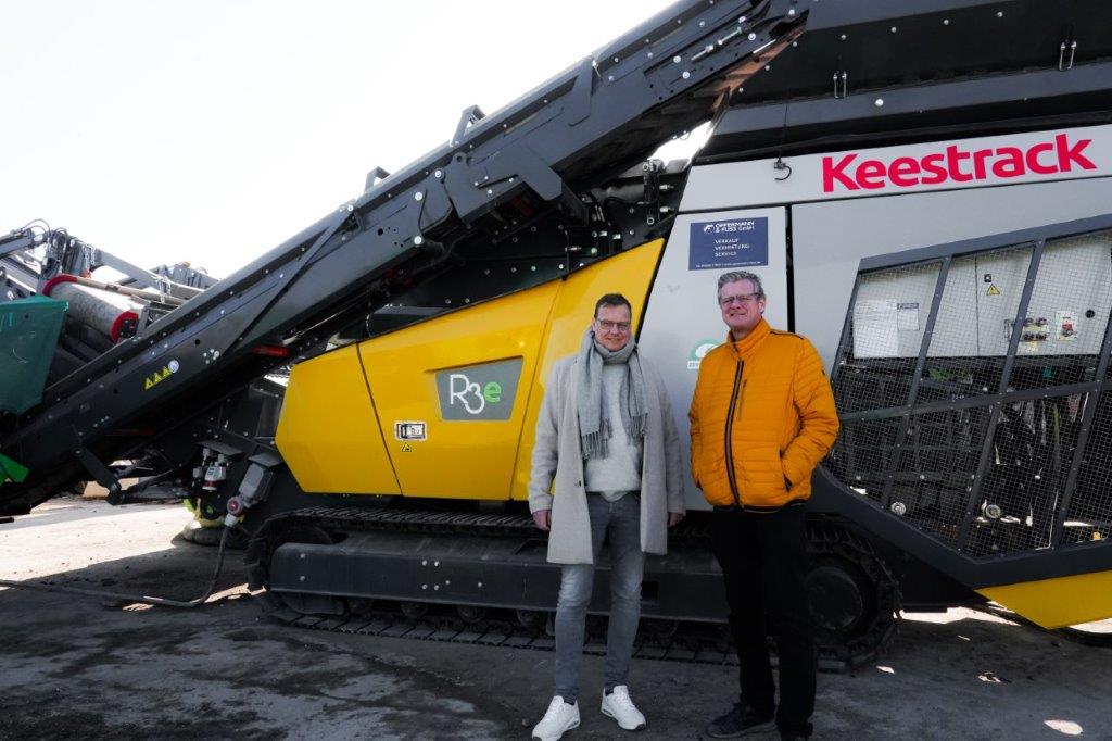 Wolfgang i Hans-Jürgen Büscher przed w pełni elektryczną kruszarką udarową R3e Zero.