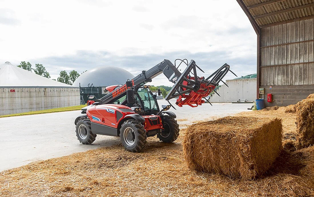 Manitou MLT 625 e – elektryczna ładowarka teleskopowa podczas pracy z belą w gospodarstwie.